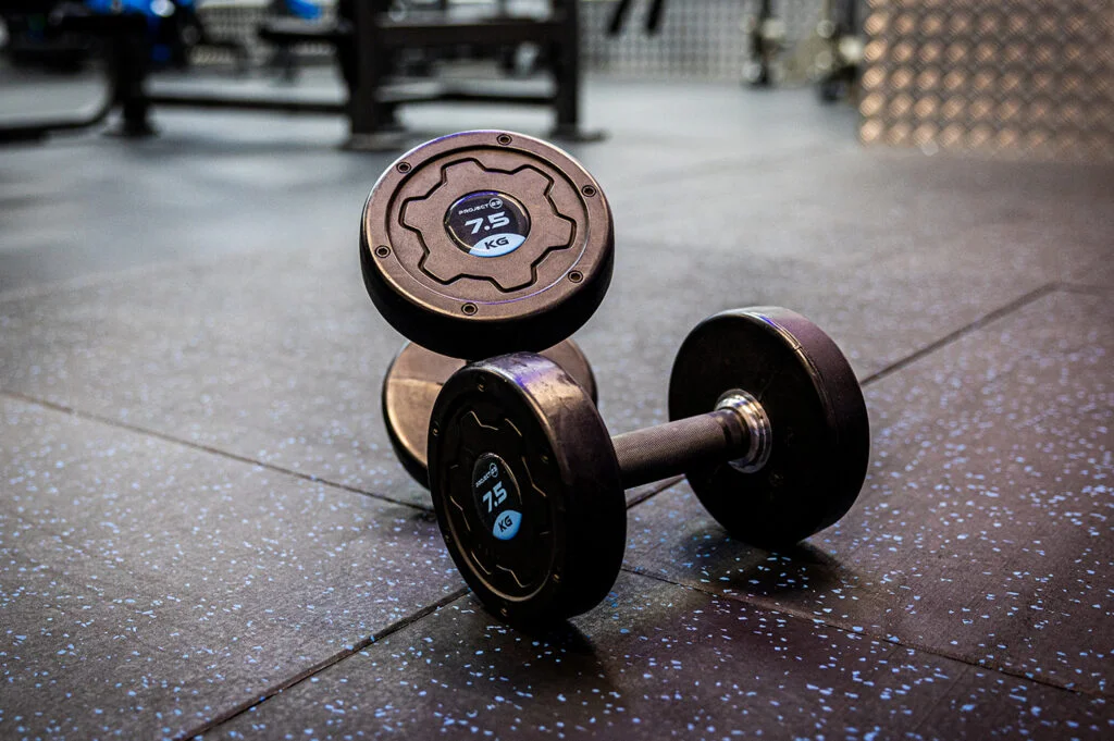 Commercial rubber gym flooring beneath free weights in a strength training area